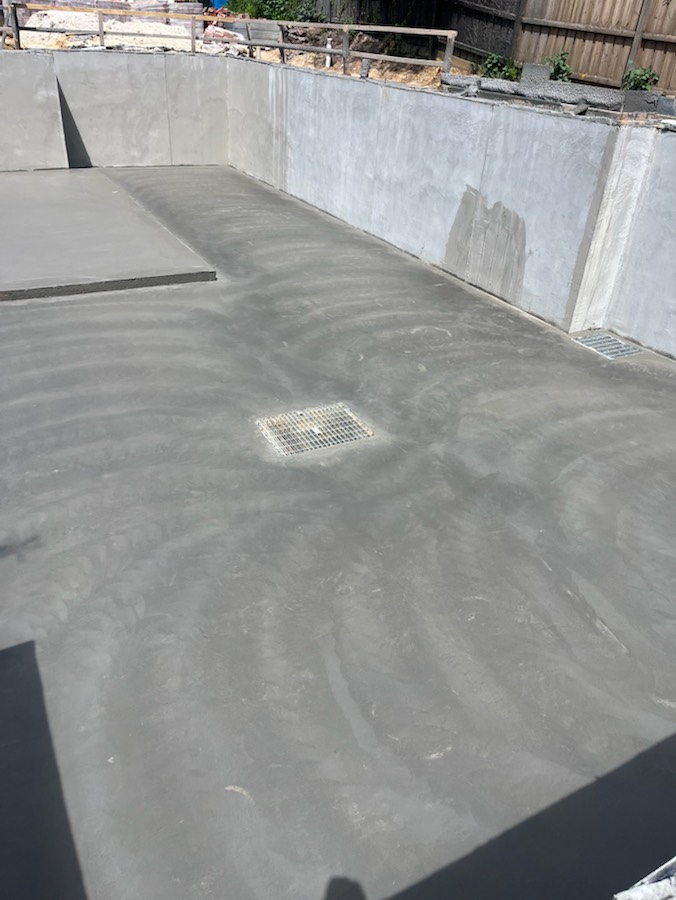 A basement slab graded to a drain, with concrete walls around it