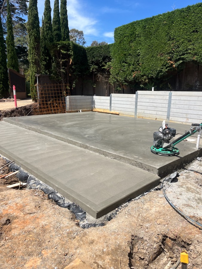 A finished slab with a stepped edge and a power trowel sitting on it